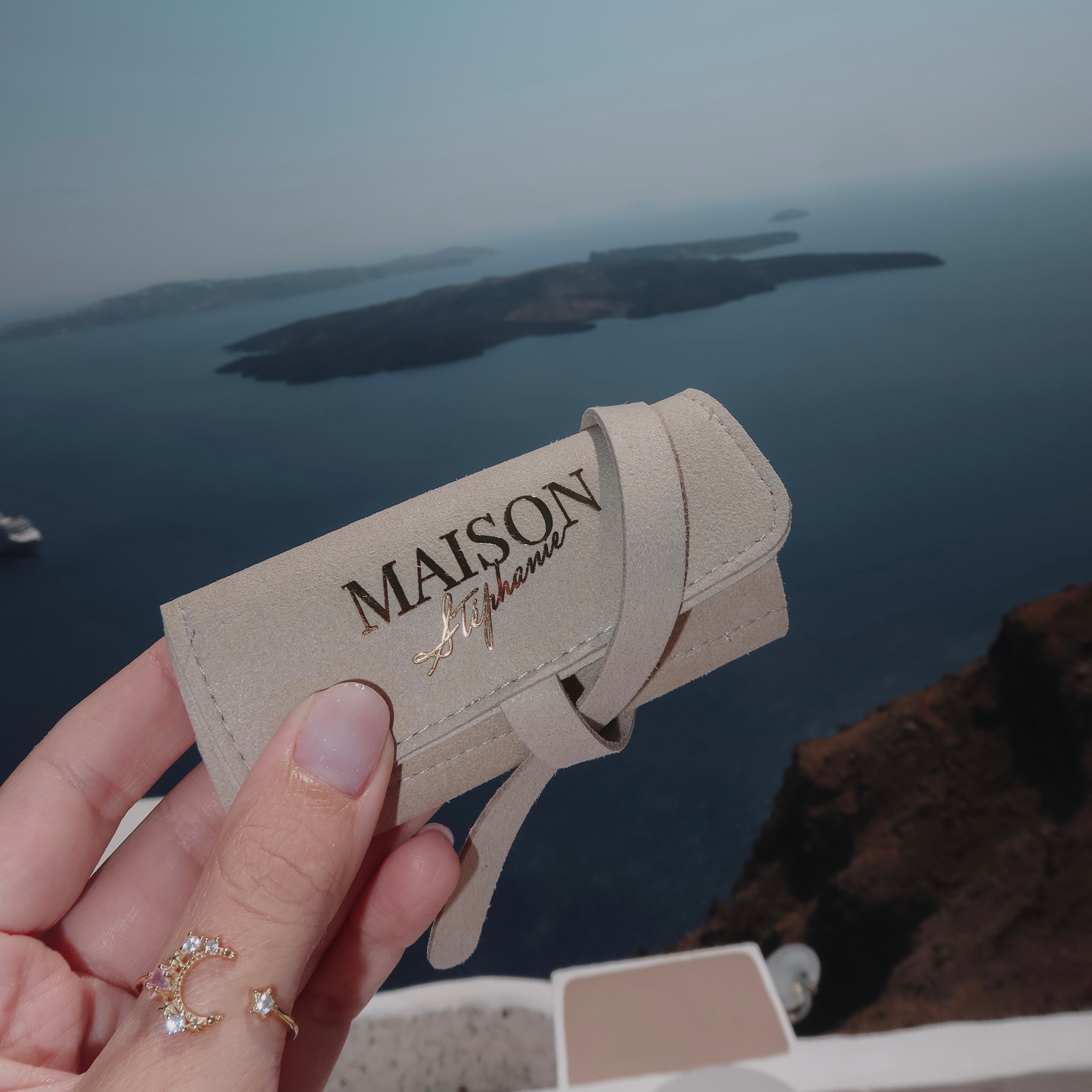 Travel Pouch MAISON Stéphanie Taupe rulat și închis, pregătit pentru transportul în siguranță al inelelor, cerceilor, colierelor și brățărilor.