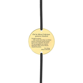 Brățară cu șnur negru și disc din argint placat cu aur 18K, gravat pe față cu Moș Crăciun în sanie și renii, iar pe verso cu un mesaj personalizat cu numele copilului.