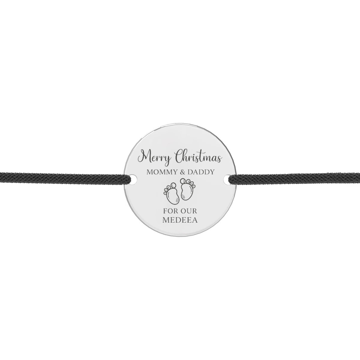 Brățară cu șnur subțire reglabil și pandantiv rotund din argint 925, gravat cu textul “Merry Christmas – Mommy & Daddy”, simbol piciorușe și numele personalizat al copilului.