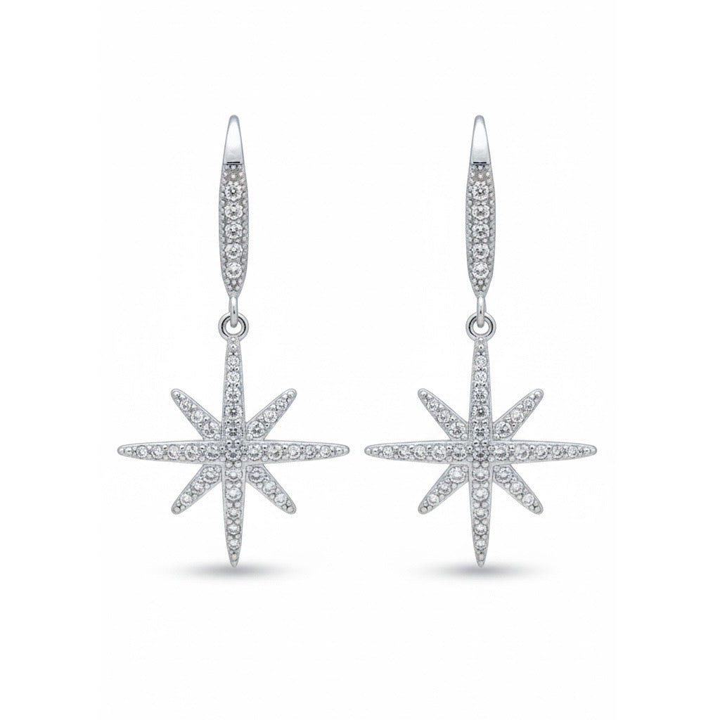 O pereche de cercei lungi din argint, cu un element superior subțire și un pandantiv în formă de floare de gheață, decorat cu pietre transparente care reflectă lumina.