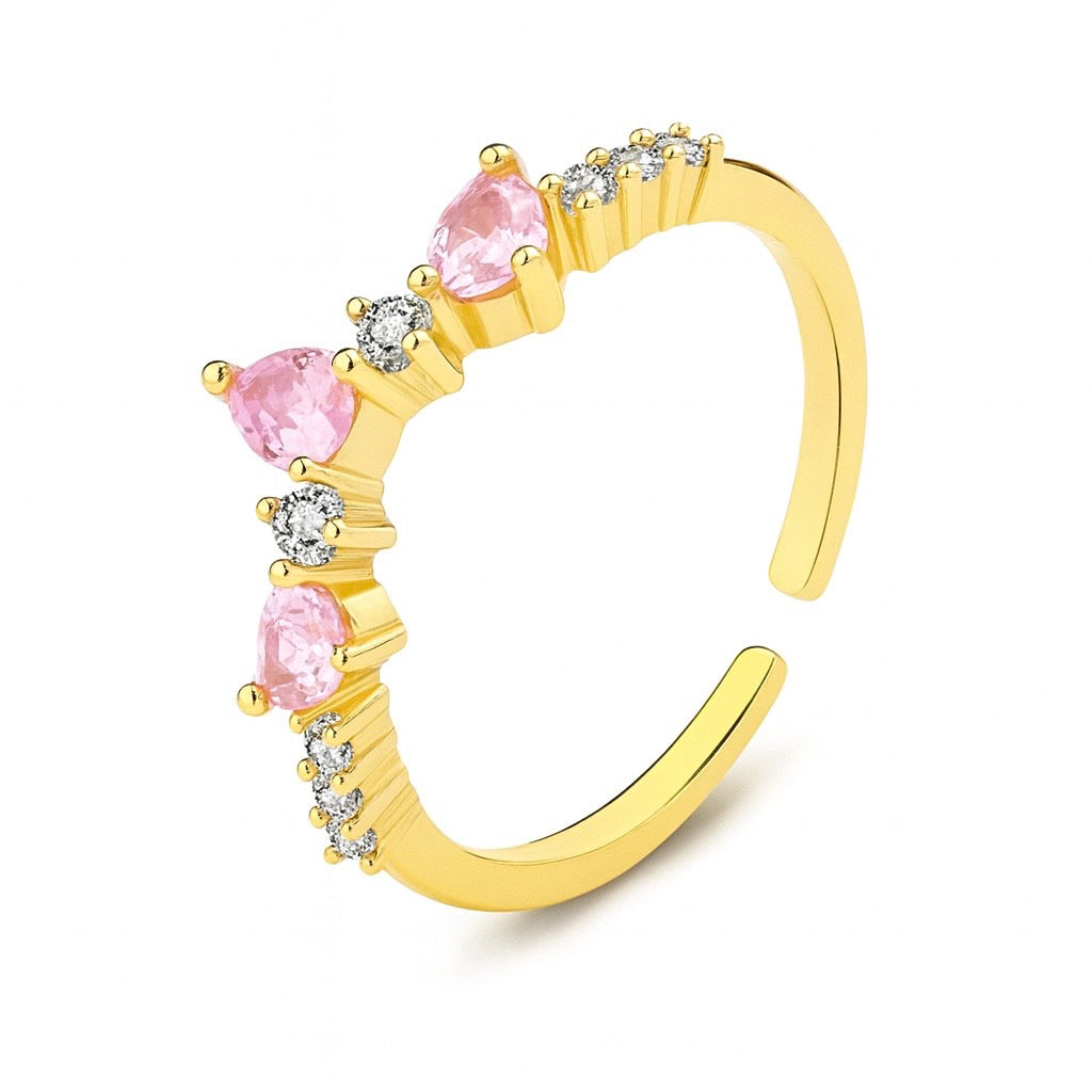 Inel reglabil din argint placat cu aur sau rodiu, cu pietre roz în formă de inimioară și zirconii mici, design curbat ce formează o coroniță delicată.