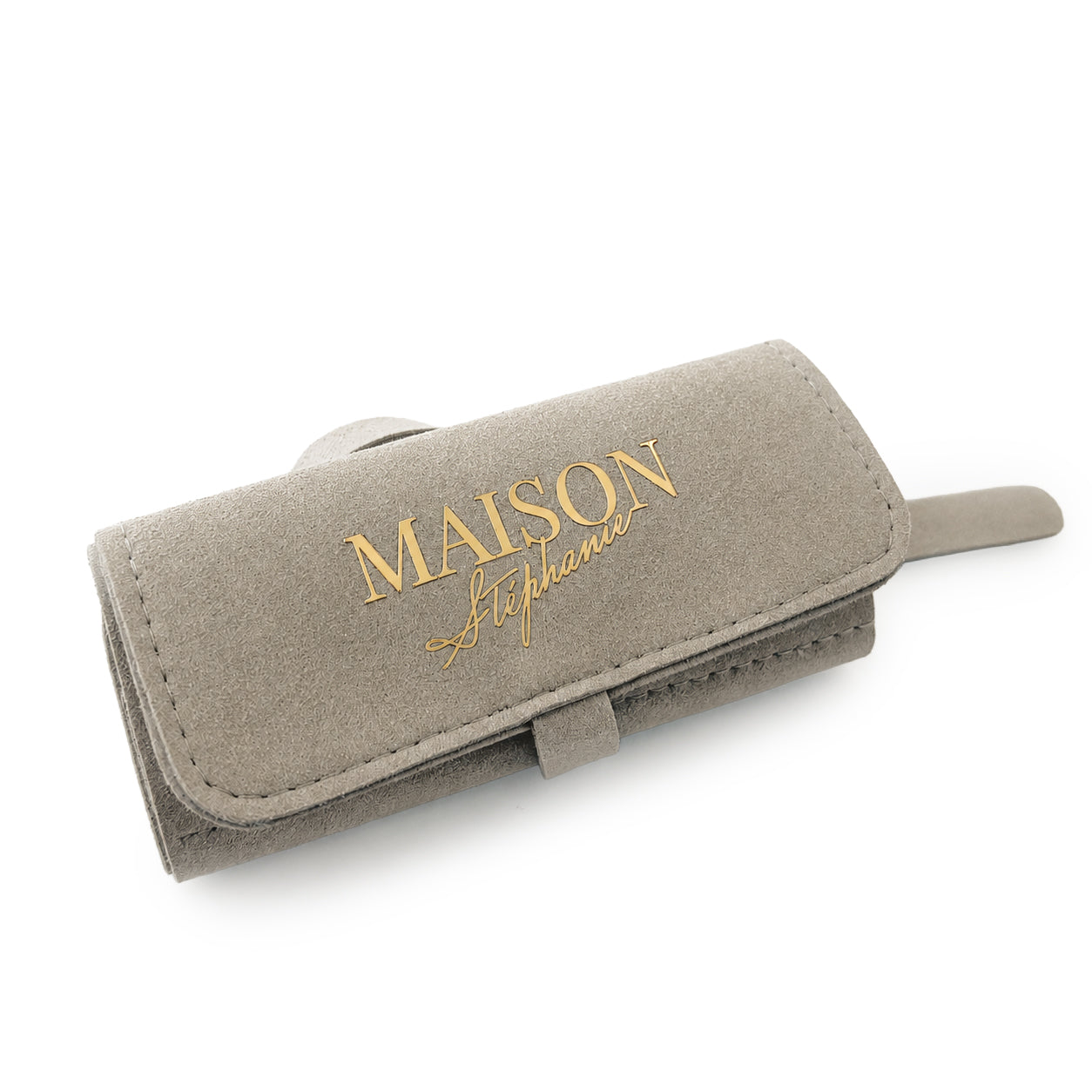 Organizator pentru bijuterii MAISON Stéphanie Travel Pouch în nuanța Taupe, fotografiat închis pe fundal alb. Exteriorul are un finisaj elegant din piele ecologică, iar în partea frontală este imprimat logo-ul auriu MAISON Stéphanie. Design compact, destinat transportului în siguranță al bijuteriilor în timpul călătoriilor.